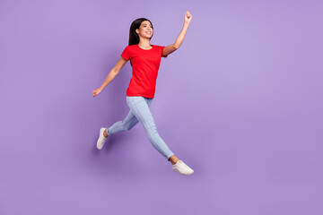Fototapeta na wymiar Full length profile photo of cute young brunette hairdo lady jump wear red t-shirt jeans isolated on violet color background