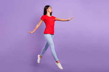 Fototapeta na wymiar Full length photo of sweet adorable woman dressed red t-shirt jumping high looking empty space smiling isolated purple color background
