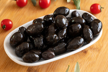 Black Kalamata olives. Tasty kalamata olives in the plate. Kalamata olives on wooden background