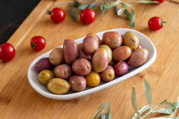 Purple kalamata olives. Tasty colored olive in the plate. Kalamata olives on wooden background