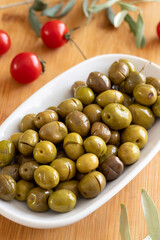 Green olive. Tasty scratched olive in the plate. Green olives on wooden background