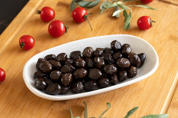 Black olive. Tasty organic black olives in the plate. Black olives on wooden background