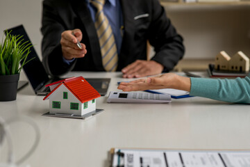 Close up house model with business man working at office,signs a purchase contract or mortgage for a home, Real estate concept.	
