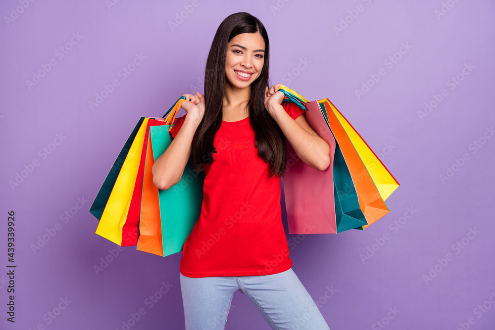 Wall mural Photo of adorable charming young lady wear red outfit smiling holding shopping bags isolated violet color background