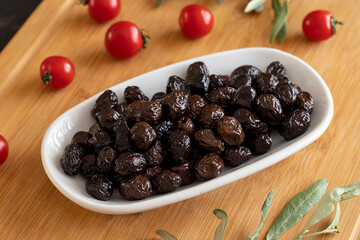 Black olive. Tasty organic black olives in the plate. Olives on wooden background