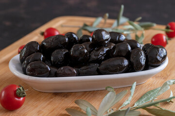 Black kalamata olives. Tasty organic black olives in the plate. Olives on wooden background