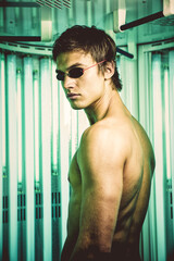 Handsome man in the standing solarium in the spa