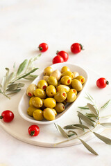 Green olives stuffed with peppers. Tasty organic green olives in the plate. Olive on marble floor