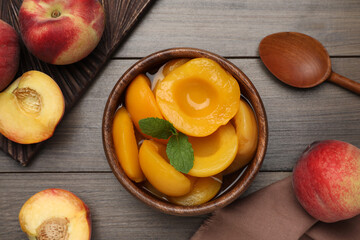 Naklejka na ściany i meble Canned peach halves in bowl on wooden table, flat lay