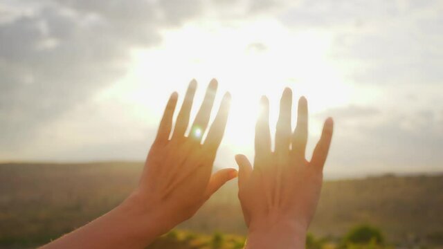Close-up view 4k video footage of 2 female beautiful hands isolated on sunny sunset sky background. Woman making gentle movements in soft sunlight