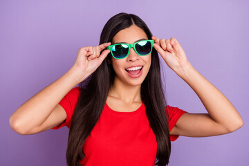 Photo of shiny excited woman dressed red t-shirt arms dark spectacles smiling isolated purple color background