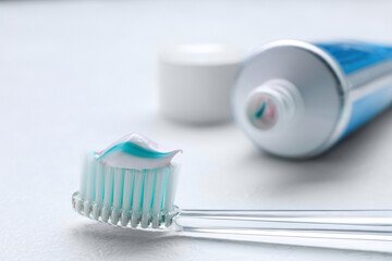 Brush with toothpaste and tube on white background, closeup