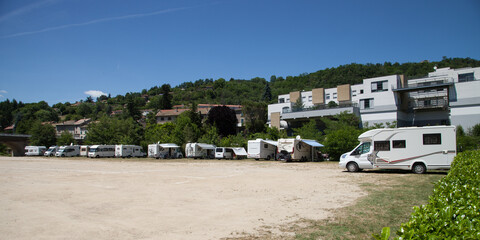 Camping cars alignés sur la place au pied de la montagne