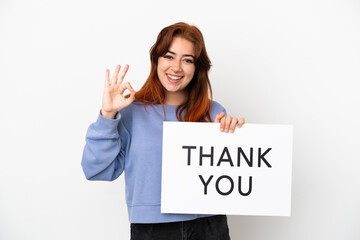 Young redhead woman isolated on white background holding a placard with text THANK YOU with ok sign