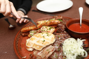 Person taking sausage from plate