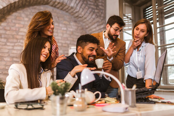 Business team working on new project and smiling. Man and women sitting together in modern office