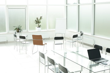 Flipchart laptop chairs and glass table in a bright office space