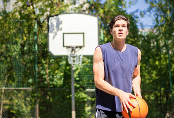Sportve young man in blue T shirt with ball in his hand playground.