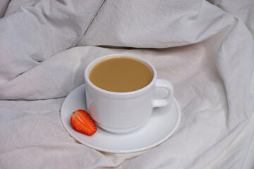 Coffee with milk on white bed linen.