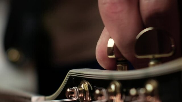 Guitarist tunes the sixth string on the guitar