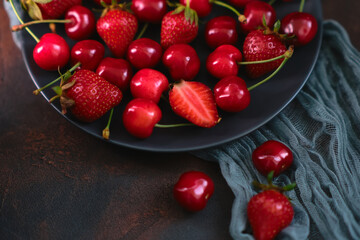 Fresh organic summer mix of strawberry and sweet cherry in round stone plate