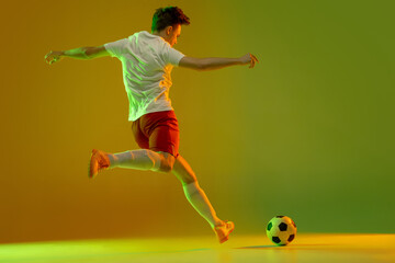 Fototapeta na wymiar One male soccer football player in action and motion isolated on gradient green yellow background in neon light