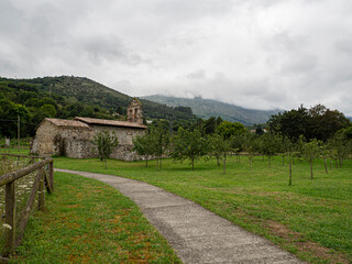 Paisajes verdes de naturaleza y medio ambiente saludable en Panes, con una iglesia al fondo, montañas, manzanos y nubes en Asturias verano de 2020