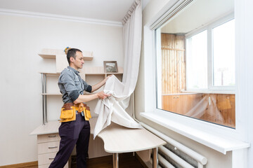 A handyman installing new cornice for curtains, home repair and renovation works © Angelov