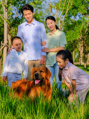 Happy family of four and pet dog playing in the park