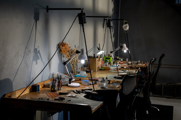 Diverse jeweller tools, lamps and other utensils lying on desk in workshop
