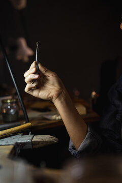 Close up of hand of caucasian female jeweller holding jeweller tools, making jewelry