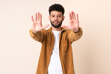 Young Moroccan man isolated on beige background making stop gesture and disappointed