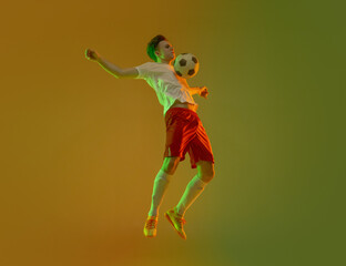 Fototapeta na wymiar Young caucasian man, male soccer football player training isolated on gradient yellow green background in neon light