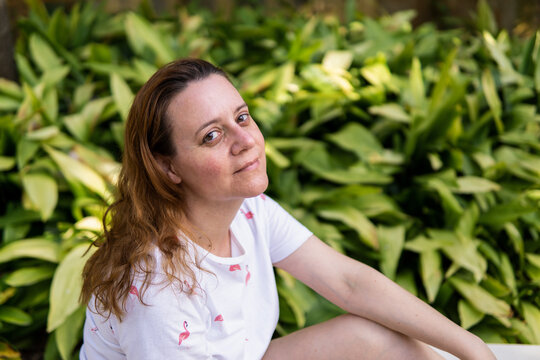Retrato de una mujer guapa caucasiana sonriendo sentada en un parque