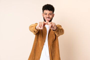 Young Moroccan man isolated on beige background making stop gesture with her hand to stop an act - obrazy, fototapety, plakaty
