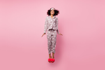Photo of pretty sweet wavy dark skin lady dotted sleepwear jumping high isolated pink color...