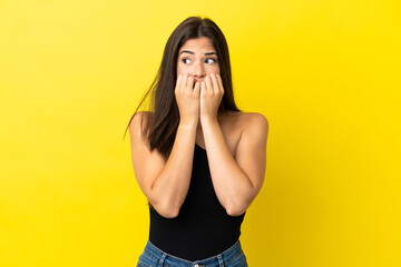 Young Brazilian woman isolated on yellow background nervous and scared putting hands to mouth