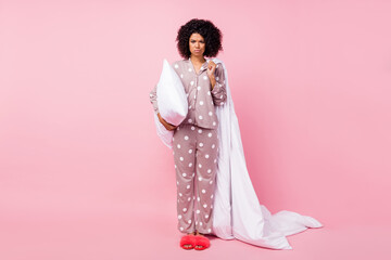 Photo of tired upset curly dark skin woman dotted nightwear holding white pillow duvet isolated...