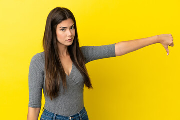 Young Brazilian woman isolated on yellow background showing thumb down with negative expression
