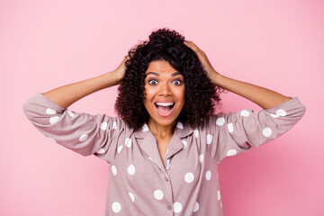 Photo of impressed funny wavy dark skin lady dotted sleepwear arms head open mouth isolated pink color background