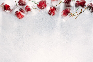 a few frozen cherry berries lie on a light stone background