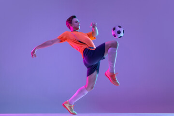 Fototapeta na wymiar One male soccer football player in action and motion isolated on gradient lilac pink background in neon light