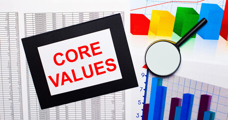 On the table there are reports of multi-colored charts, a magnifying glass and a sheet of paper in...