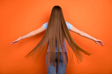 Back side photo of millennial long hairdo lady wear blue t-shirt jeans isolated on orange color...