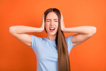 Photo of yell brown hairdo young lady close ears wear blue t-shirt isolated on vivid orange color background