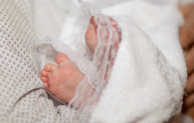 The sacrament of the baptism of a child in an Orthodox church, the baby's feet in a white veil...