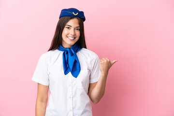 Airplane stewardess Brazilian woman isolated on pink background pointing to the side to present a product