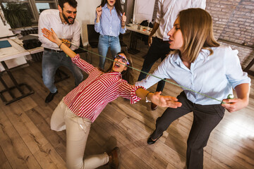 Group having fun together with limbo game at office party. - obrazy, fototapety, plakaty
