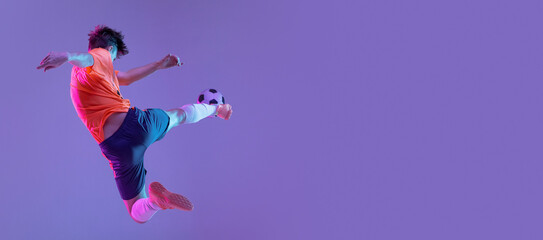 Young caucasian man, male soccer football player training isolated on gradient blue pink background...