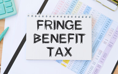 FRINGE BENEFIT TAX - text on a note sheet against the background of a calculator and a pen. Business and finance concept.